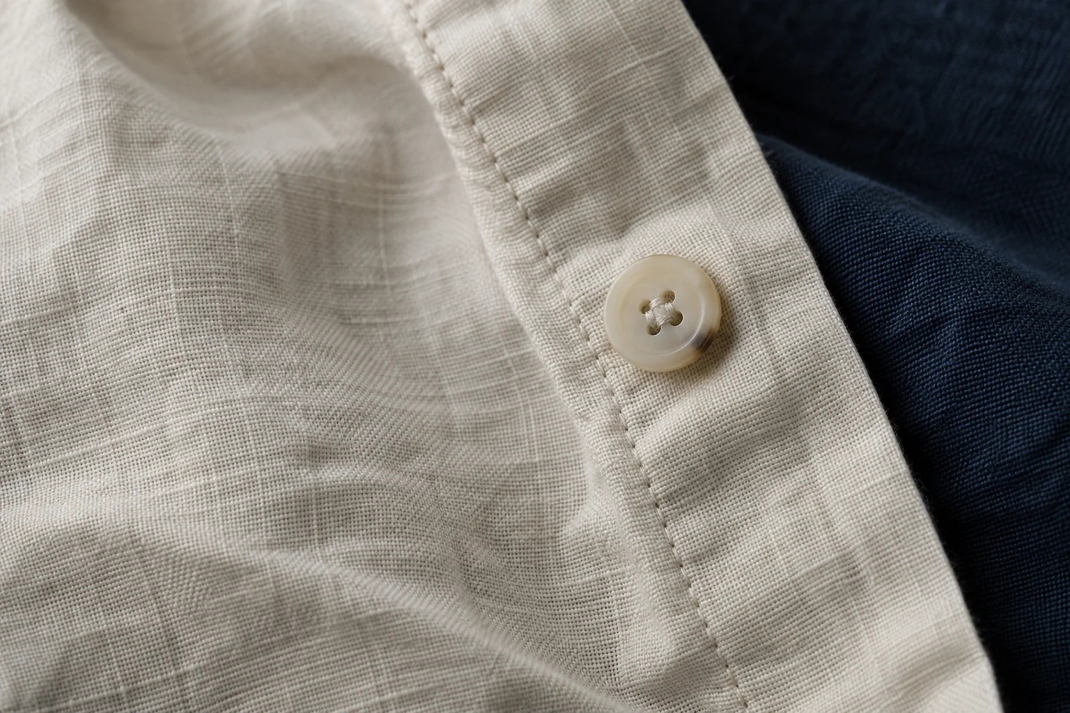 Detalle de costura y botón sobre tejido de lino